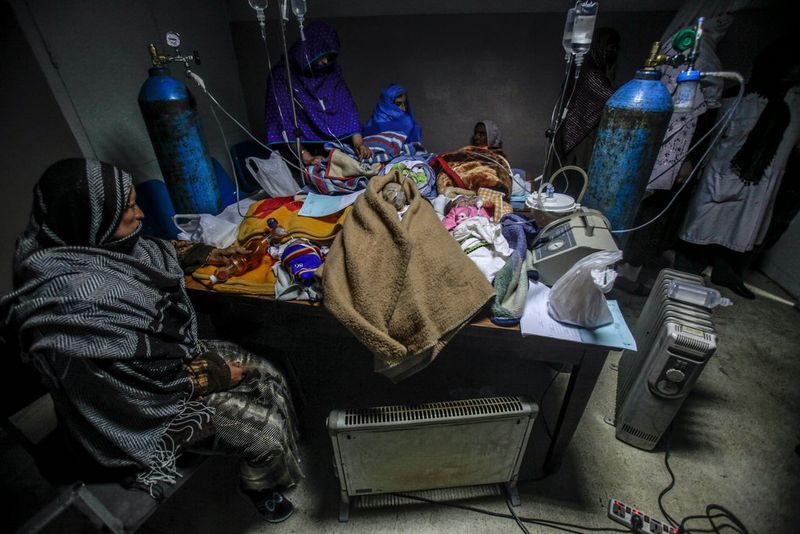 Women looking at their babies on a medical table at a hospital in Kabul, Afghanistan.
