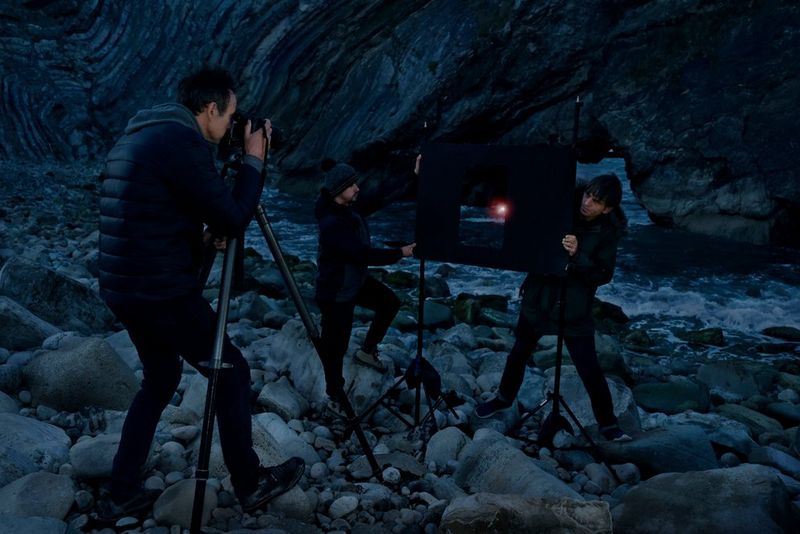 Rob Payne taking a multiple exposure photograph of a rocky coastline. A stencil of a doorframe is positioned in front of the camera.
