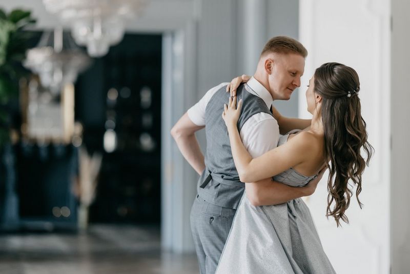 Пара танцует — жених поддерживает невесту за спину, а она обнимает его за плечи.