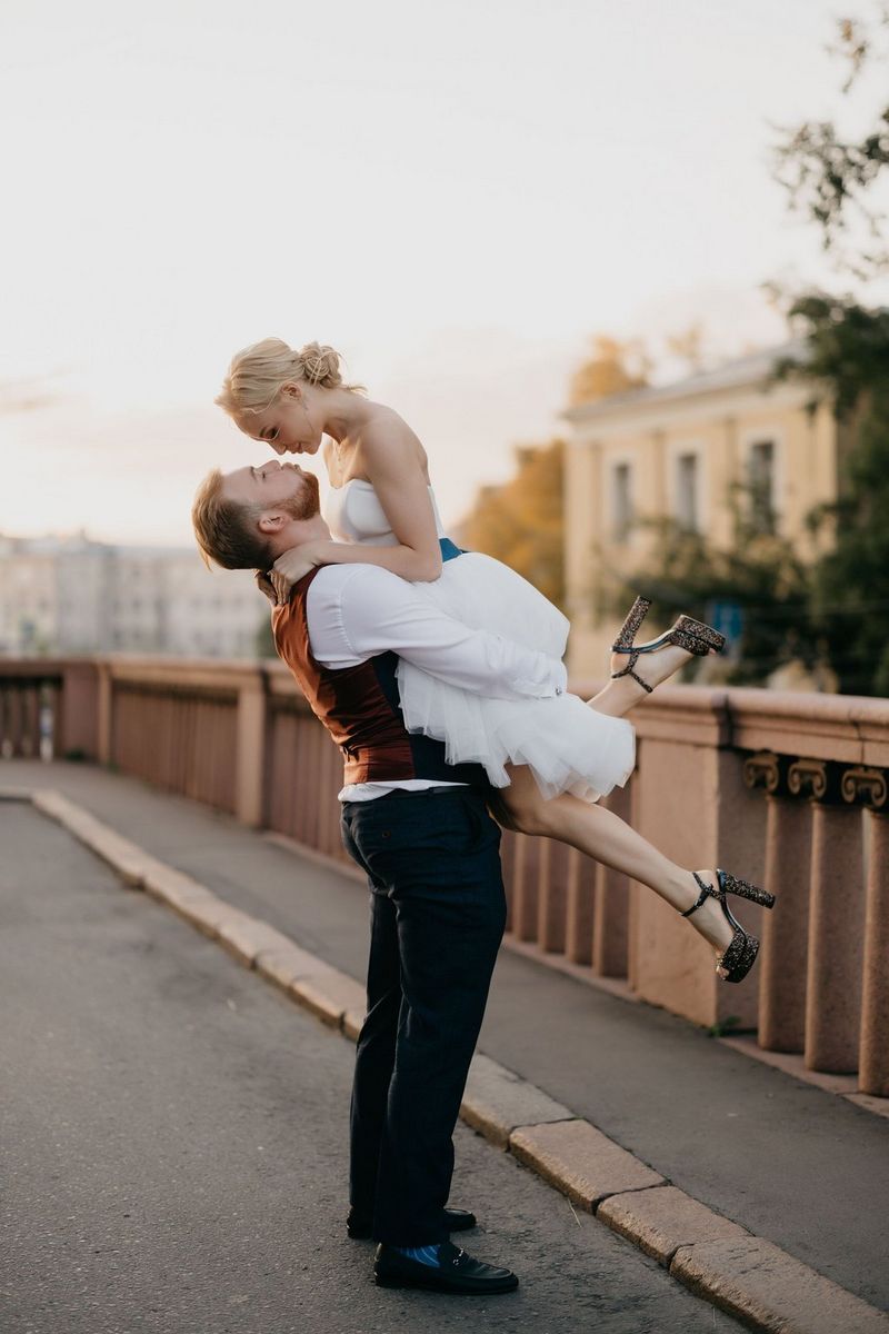 Жених поднимает невесту в воздух, отклоняясь назад, чтобы поцеловать ее.