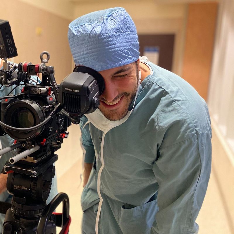 Producer Alberto Allica in hospital scrubs behind a Canon EOS C500 Mark II cinema camera.