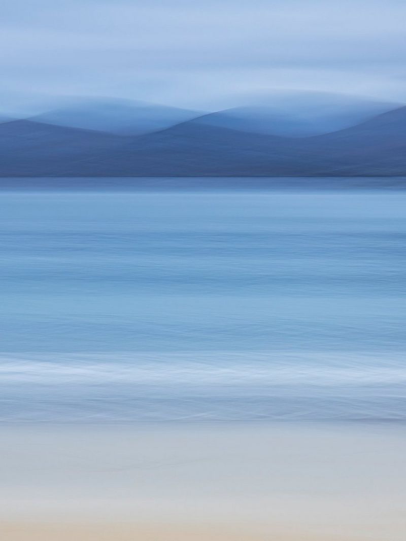 An abstract shot of a beach scene, with blurred mountains in the background. 
