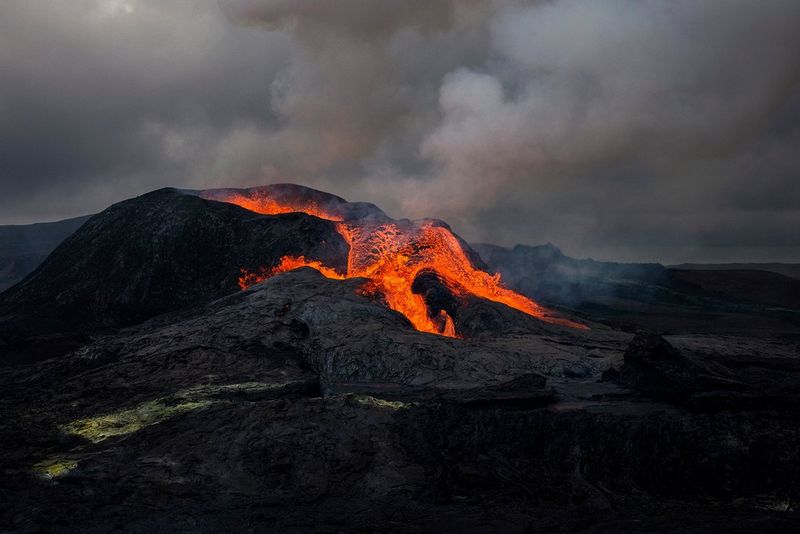 The Fagradalsfjall volcano in Iceland erupting with lava flowing out of it and smoke filling the sky. This image was captured by Paolo Pellegrin on a Canon EOS R5.