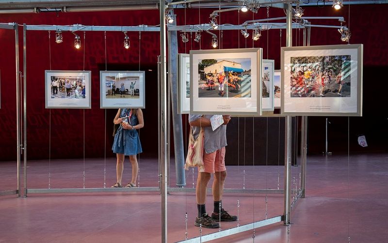 Twee personen bekijken ingelijste foto's die worden tentoongesteld op Visa pour l'Image, het internationaal festival van fotojournalistiek in Frankrijk.