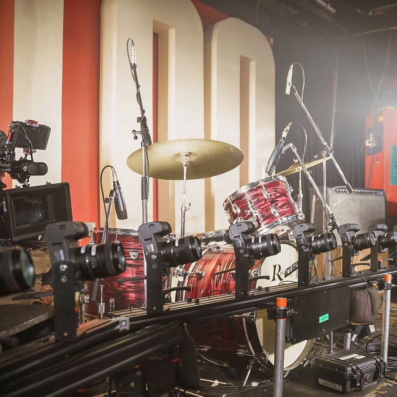 A stage containing a bar cam, an electric guitar and an elaborate drum kit. In the background, the number 100 can be seen. 