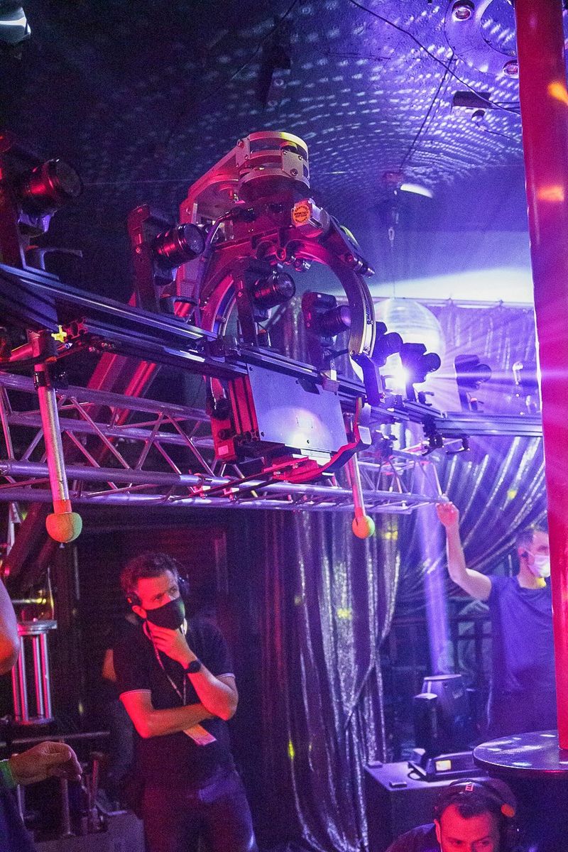 Crewleden bedienen de Canon-kit op een tv-set die baadt in helder paars licht.