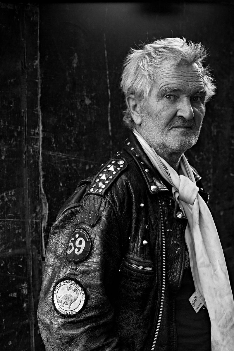 Un ritratto in bianco e nero di un uomo anziano che indossa un giacchetto di pelle.