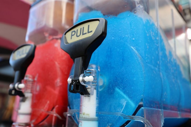 Una foto ravvicinata di due distributori di bevande contenenti del liquido rosso e blu brillante. Entrambi riportano la scritta "PULL".