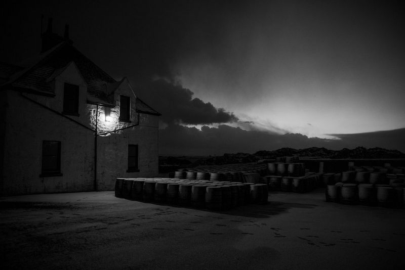 Scatto invernale in bianco e nero di botti vuote posizionate all'esterno della distilleria Ardbeg sull'isola di Islay, in Scozia.