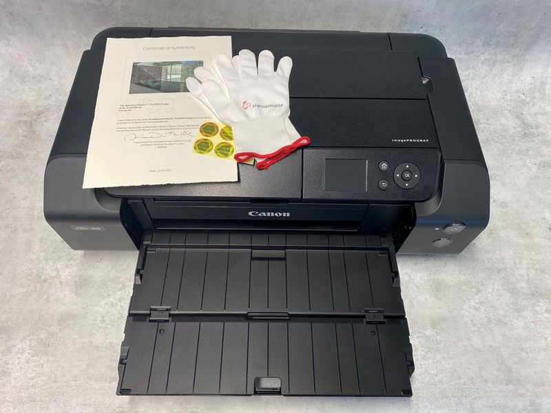 A Canon printer with a certificate of authenticity from a paper manufacturer. 