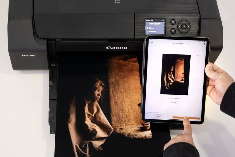 A man uses a tablet to check the settings on his Canon printer. 