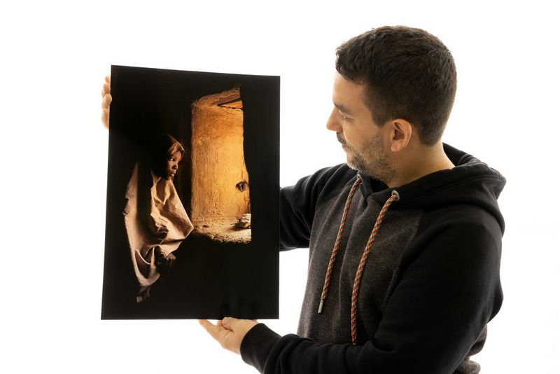 Photographer Joel Santos admires a portrait print of a photograph of a woman inside a Nigerian mosque.