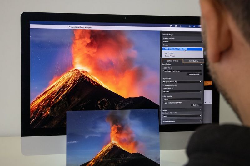 Een man past printinstellingen aan met de Canon Professional Print & Layout-software op zijn computer. Op zijn scherm staat een foto van de stratovulkaan Volcán de Fuego in Guatemala.