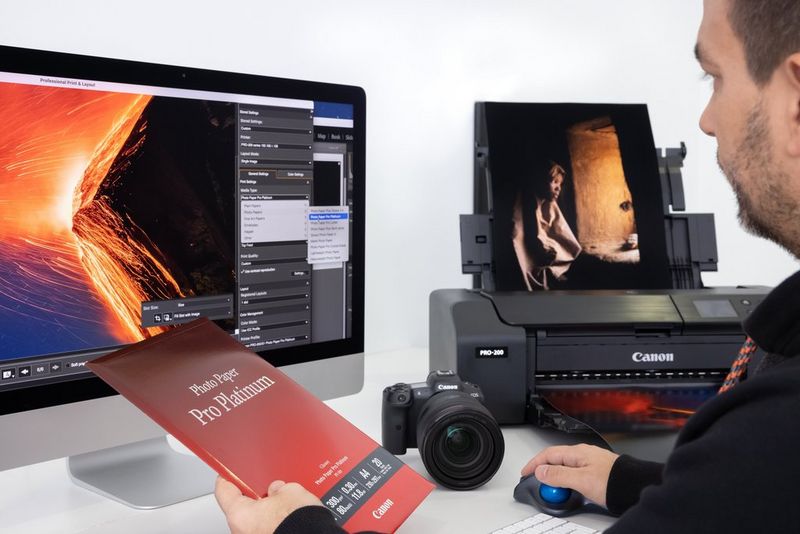 A man prepares to print the image on his computer screen using a Canon printer and Canon paper. 