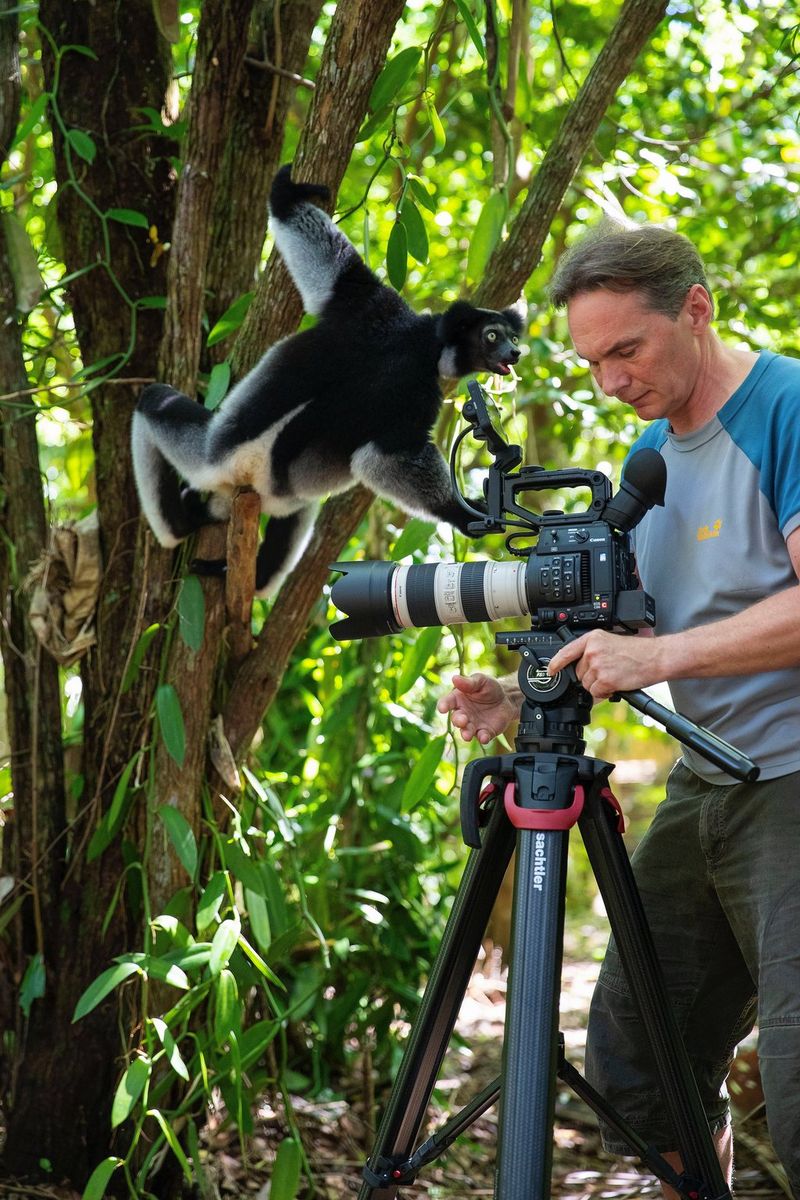 Il fotografo naturalista Thorsten Milse si prepara a scattare la foto di un lemure bianco e nero appeso a un albero.