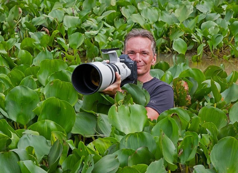 Il Canon Ambassador Thorsten Milse circondato dalla vegetazione, con la sua fotocamera Canon e l'obiettivo puntato, pronto a scattare.
