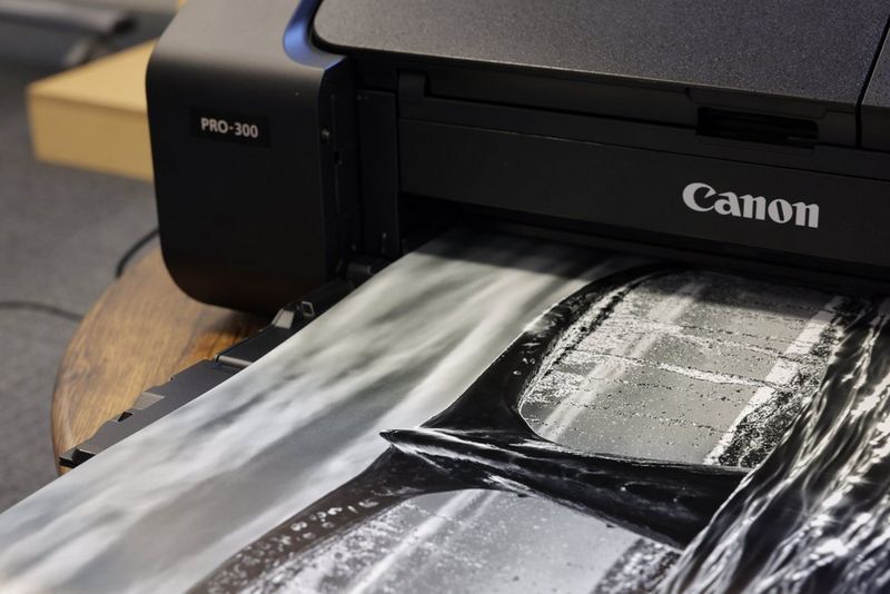 A black and white print of a whale's tale emerges from a Canon imagePROGRAF PRO-300 printer. 