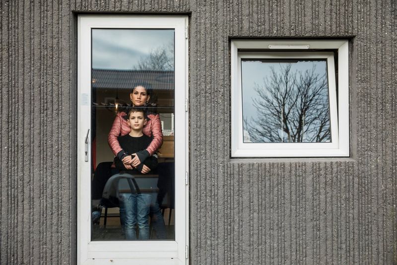 A mother and her son posing for a portrait behind a glass door. 