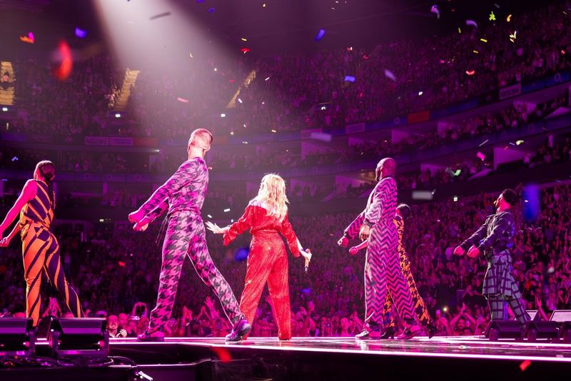 Kylie Minogue performing in front of a large audience at a London arena, with a Canon PTZ camera tracking her movement.