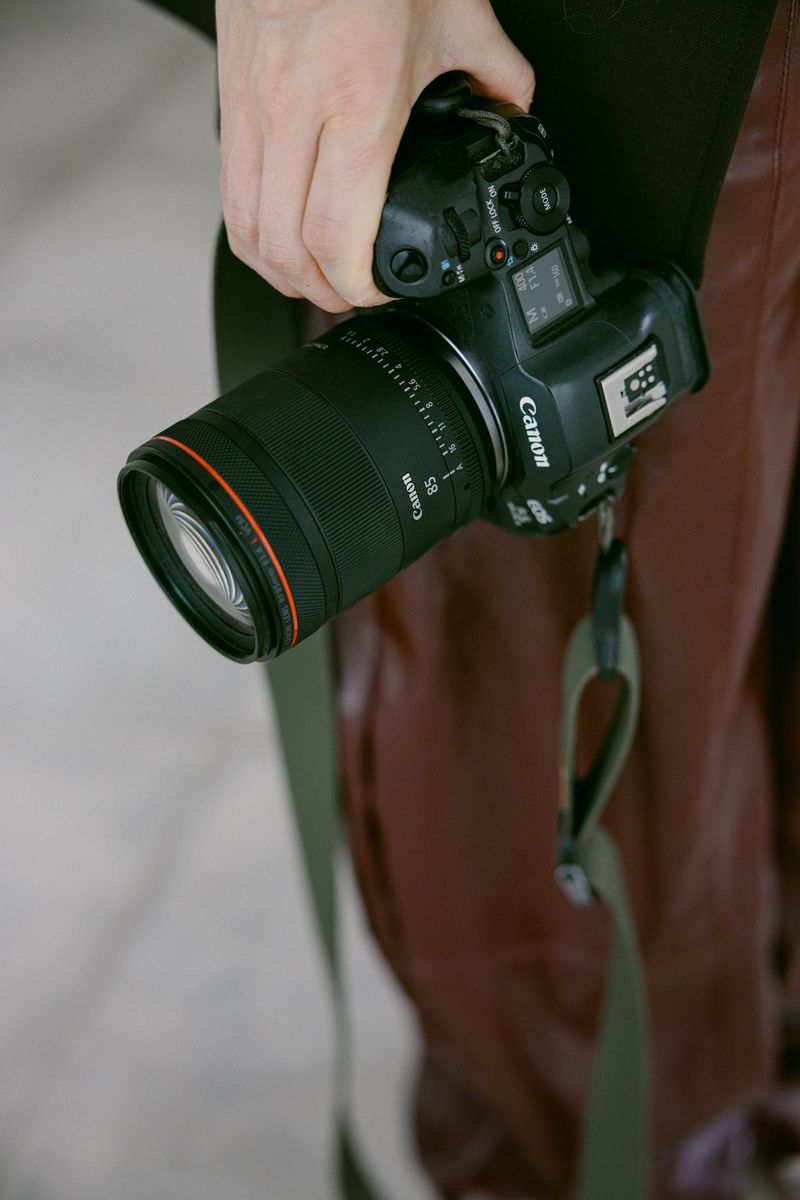 Wedding photographer Raïs De Weirdt holds a Canon EOS R5 Mark II with a Canon RF 85mm F1.4L VCM lens in one hand by her side.