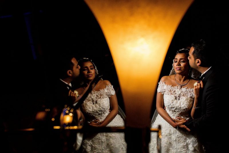 Een bruidegom kust het gezicht van zijn bruid, het paar perfect weerspiegeld in de spiegel links op de foto.