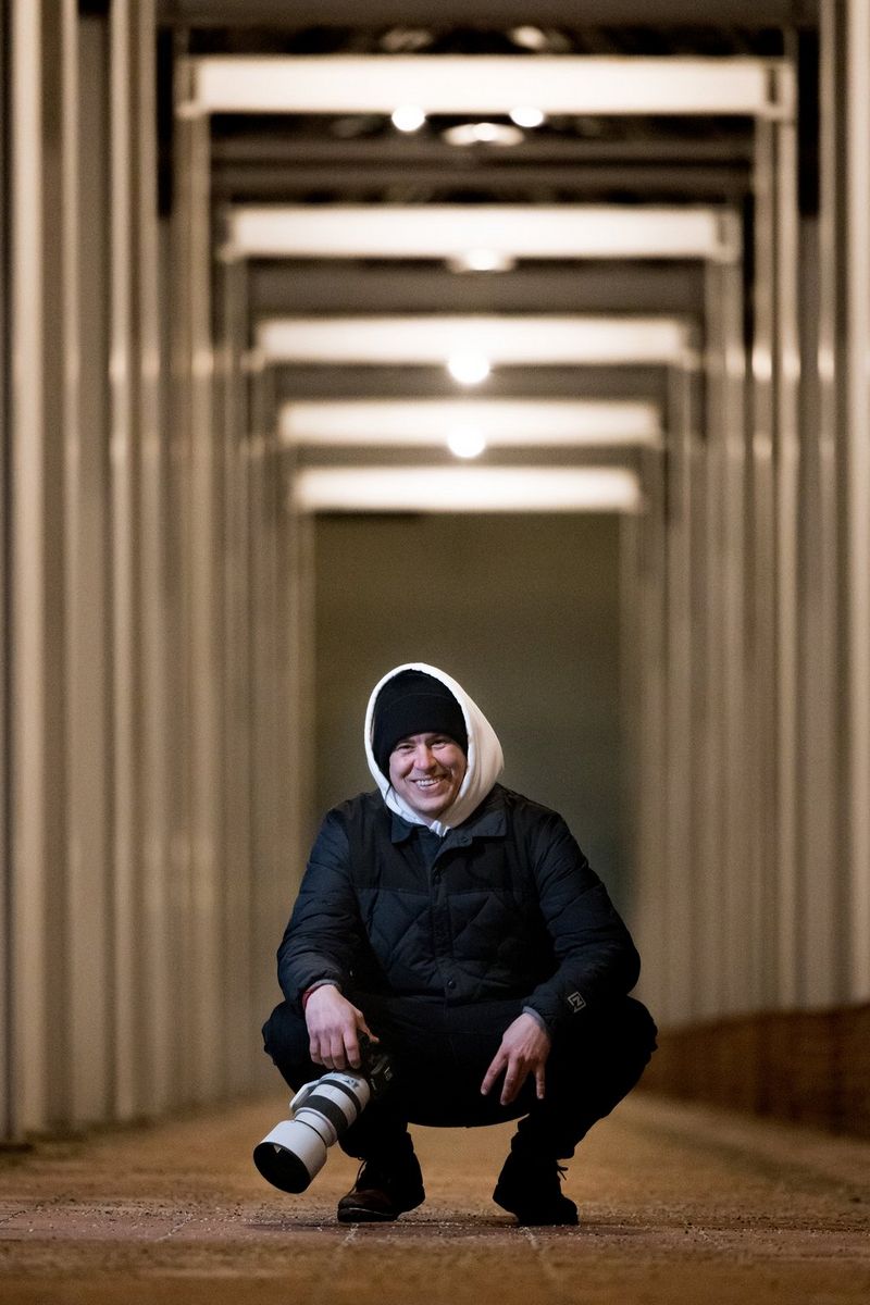 Mentor Lorenz Holder van de Canon Redline Challenge zit gehurkt met een Canon EOS R5 in zijn handen.