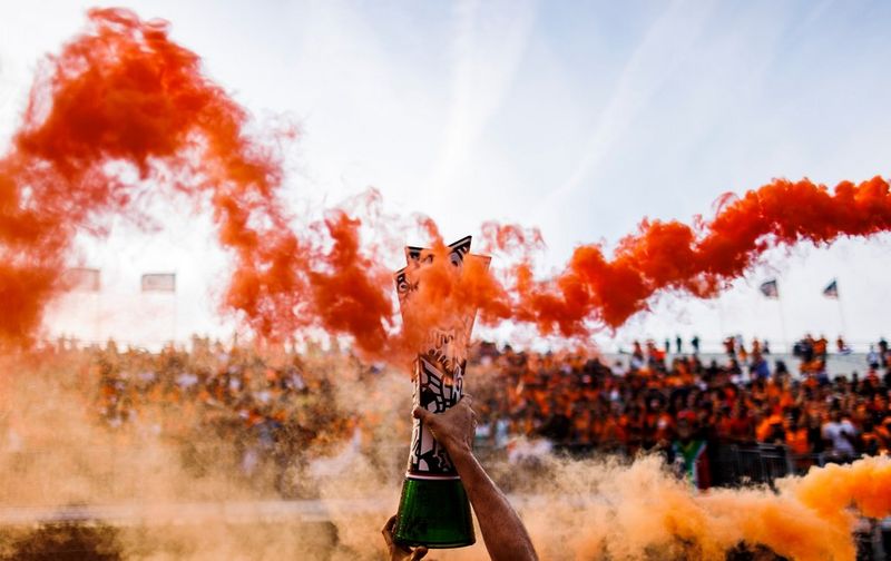 Fumo rosso e arancione che si spande sulla folla durante un evento sportivo.