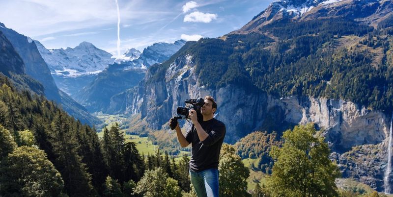 A man filming on a mountain in the Swiss Alps with a Canon Cinema EOS camera. 