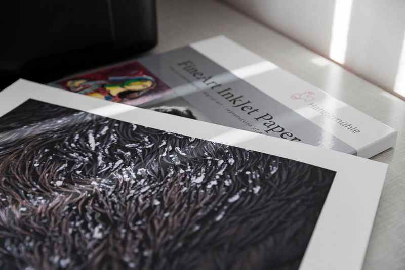 Un tirage photo posé sur une boîte de papier d'impression beaux-arts.