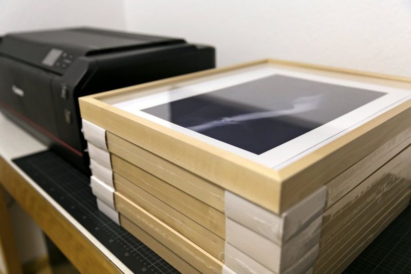 Une pile de tirages encadrés à côté de l'imprimante Canon de Richard Walch.