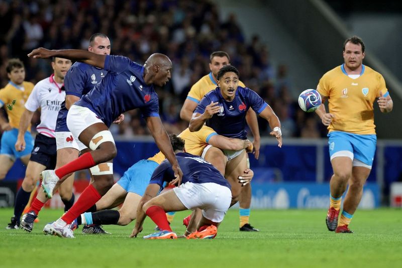Due giocatori francesi corrono per prendere il pallone, mentre gli avversari uruguaiani hanno lo sguardo in camera, in uno scatto realizzato alla Coppa del Mondo di rugby 2023 con Canon EOS R3 da Valentine Chapuis.