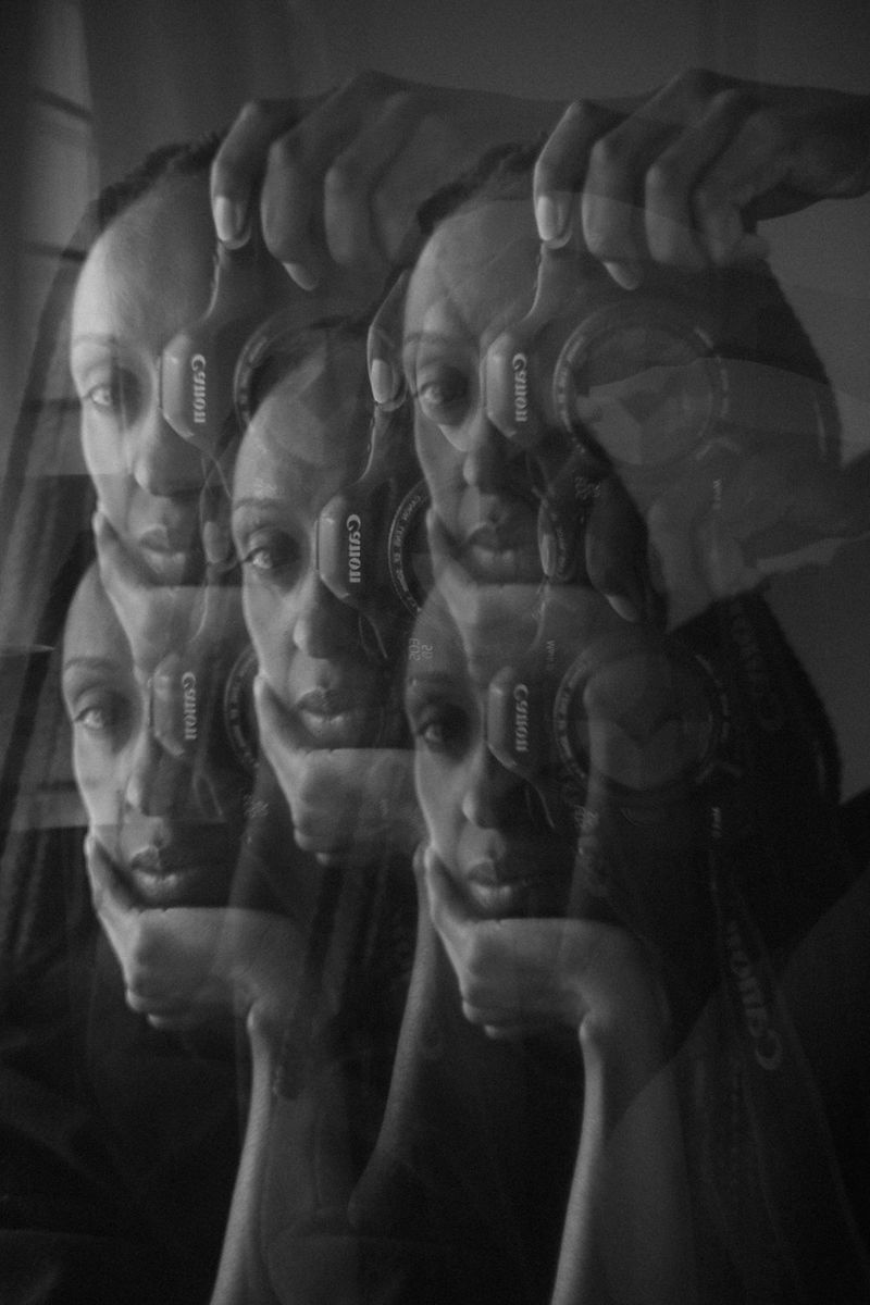 A black and white multiple exposure of photographer Sarah Waiswa holding a Canon camera.