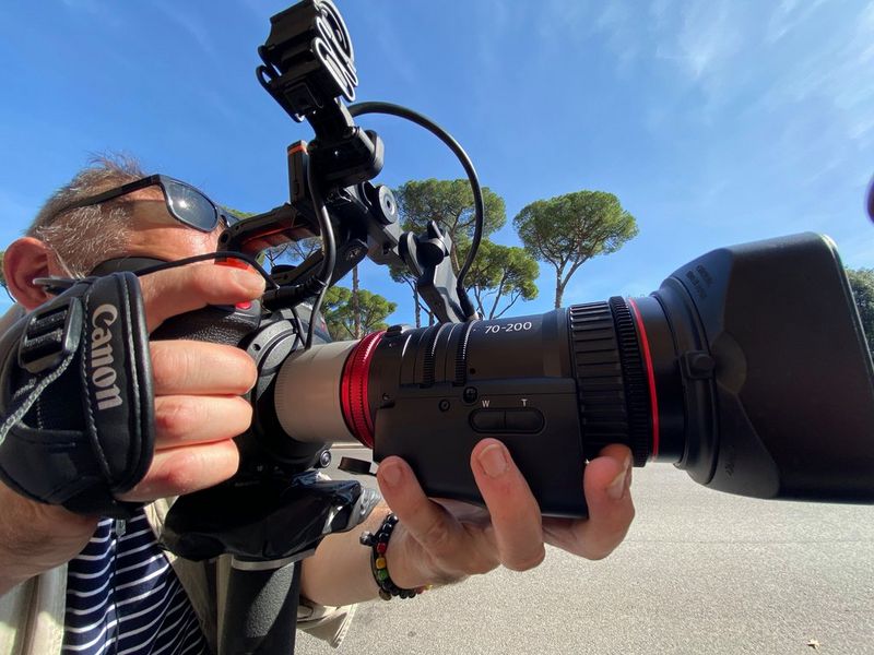Un uomo con in mano una videocamera Canon EOS C300 Mark II e un obiettivo Canon CN-E70-200mm T4.4 L IS.