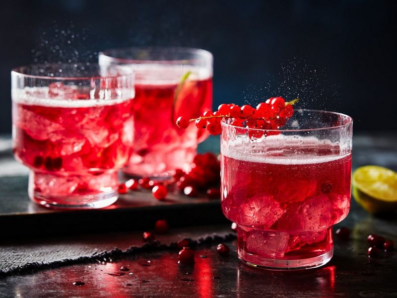Three glasses of a cranberry drink, filled with ice, fizz temptingly.