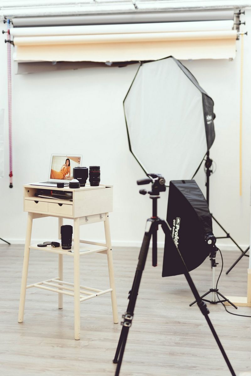 Parte dello studio di Evely Duis, tra cui un treppiede con riflettore, un tavolino con vari obiettivi Canon e un computer portatile aperto, sul cui schermo si vede una foto.