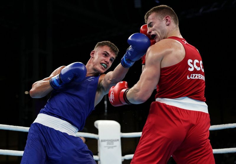 Two boxers are captured in the ring, one landing a blow against the other's face.