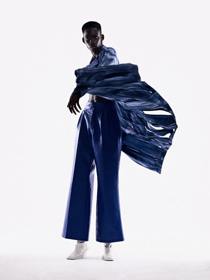 A portrait taken on a Canon EOS R5 of a model dressed in dark blue caught in motion against a white background.