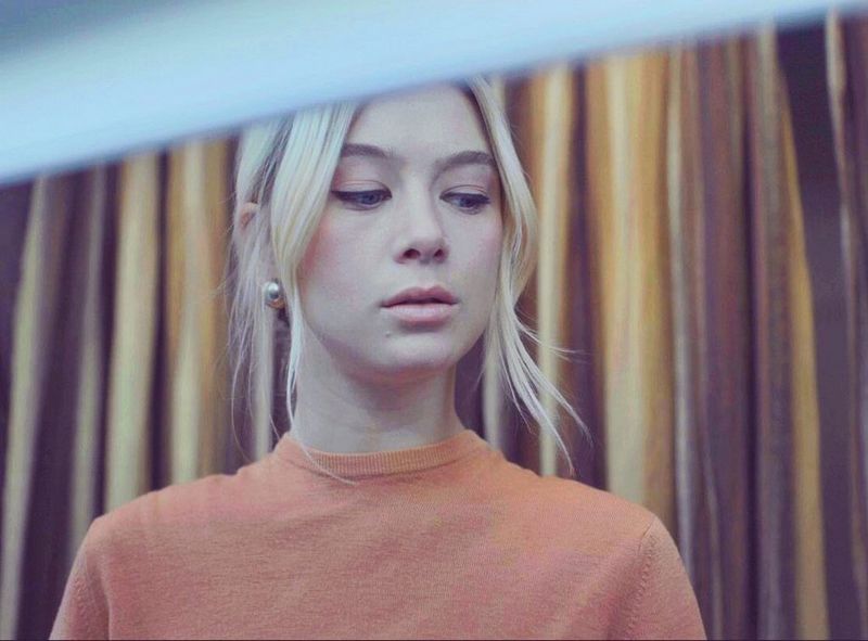 A blonde-haired woman looking pensively downwards. 