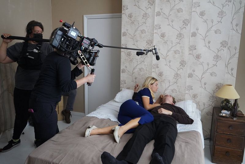 A small crew films actors Eloise Smyth and Bill Milner lying on a bed during filming of the Cynthia Lennon biopic Cyn.
