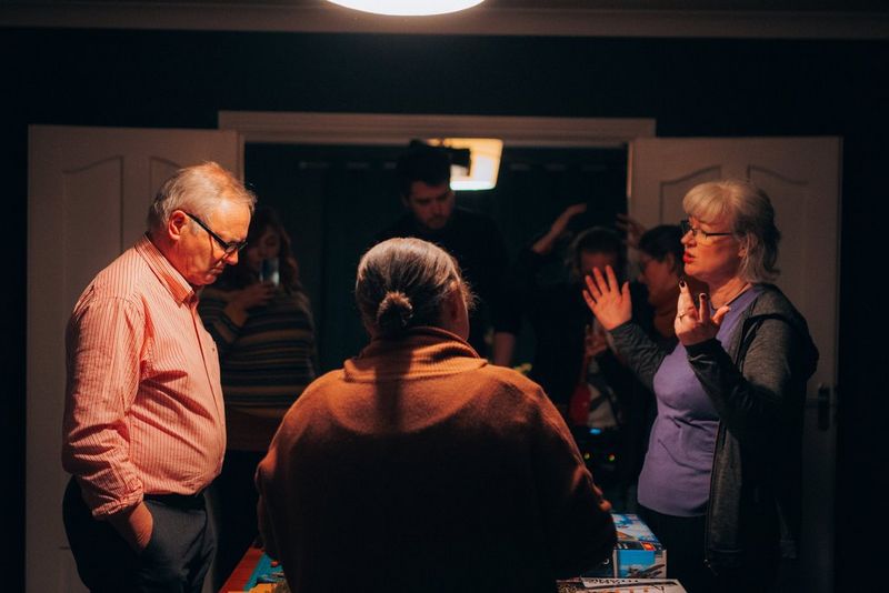 Several people stand around a dining table discussing the filming of a scene from the film Verdigris, shot by cinematographer Tania Freimuth.