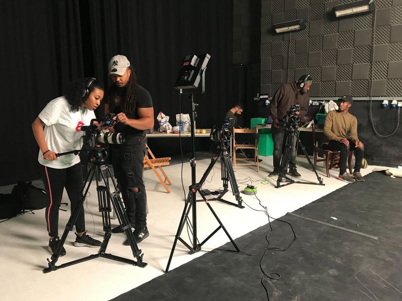 Несколько человек настраивают камеры в большом помещении.