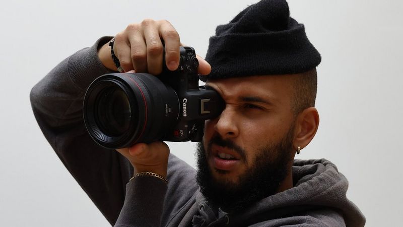 Een man houdt een Canon EOS R5 C voor zijn gezicht en kijkt door de zoeker.