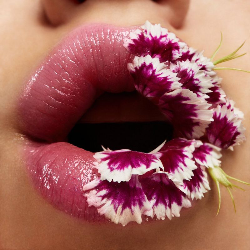 A pouting pair of lips half covered in tiny pink and white petals, which match the outline perfectly.