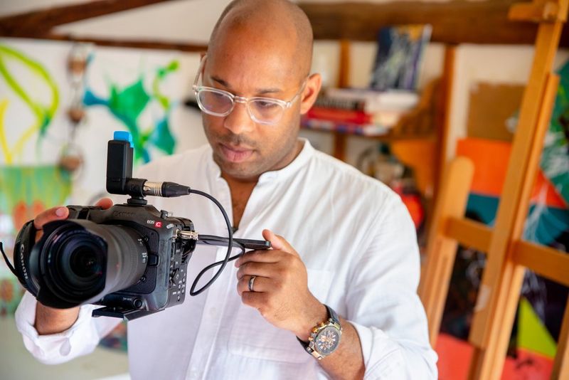 A close-up of a man filming with a Canon EOS C70 camera.