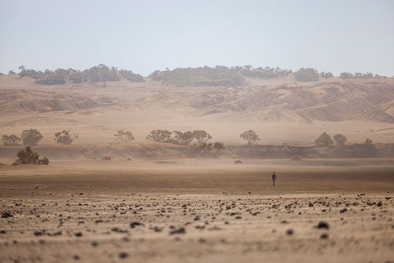 На фотографии, снятой на камеру Canon EOS R5, изображена одинокая фигура на фоне пыльного вулканического пейзажа.