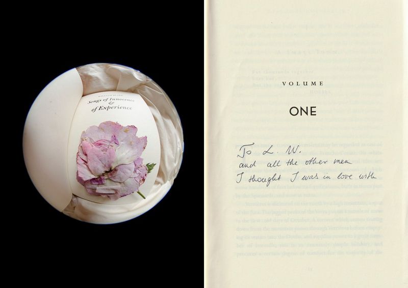 A wilting rose on the title page of a book taken from above with a fisheye lens next to a second page with a handwritten note on it. 
