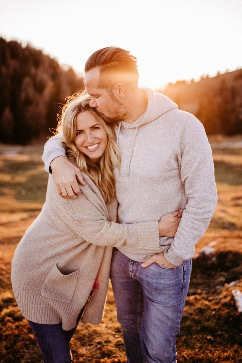 Autoritratto della coppia di fotografi di matrimoni Carmen e Ingo che si abbracciano mentre il sole tramonta dietro di loro.