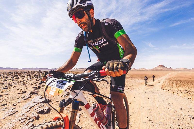 A person riding a mountain bike in the foreground with desert stretching out behind them.