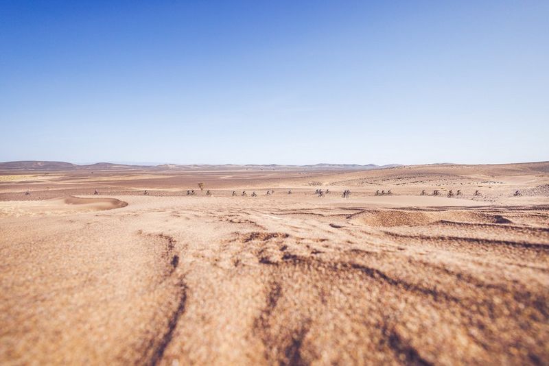A sprawling desert landscape with cyclists captured in the far distance.