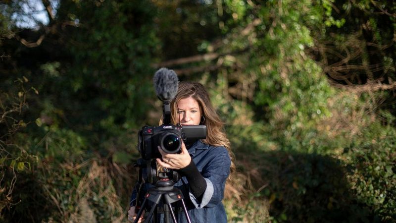 Une femme tient un appareil Canon et règle l'objectif monté.